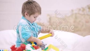 幼儿玩五颜六色的玩具积木.. 孩子们玩。 小男孩在白色的床上搭建积木玩具塔